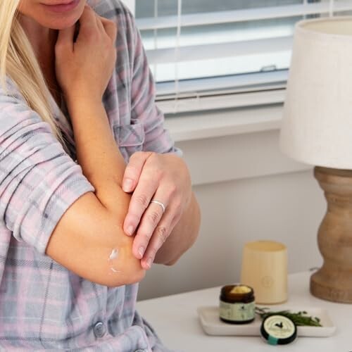 Woman applying cream to her elbow in a cozy setting