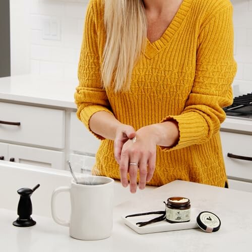 Woman in yellow sweater applying cream in kitchen