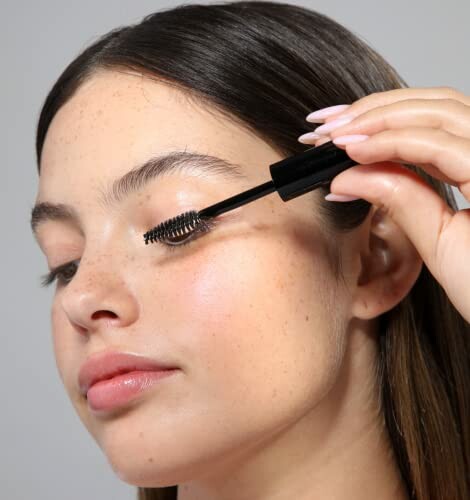 Woman applying mascara to eyelashes