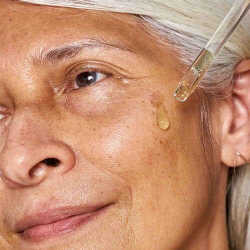 Close-up of woman applying facial serum with dropper.