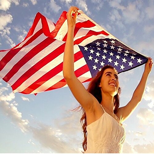 Woman holding American flag under blue sky