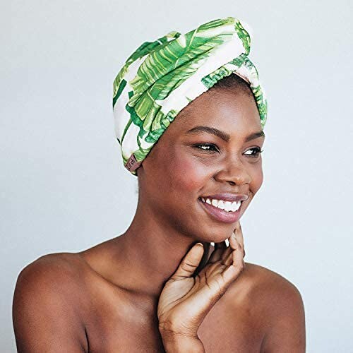 Woman smiling, wearing a leaf-patterned hair turban.